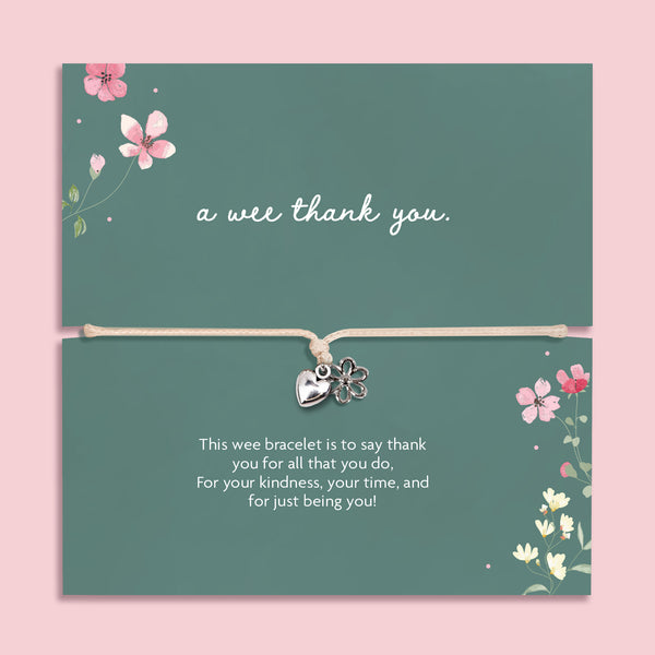 Silver heart and flower charm bracelet on an adjustable cord displayed on a green floral card featuring the Scottish phrase “a wee thank you”. Meaningful thank you gift for friends, teachers, coworkers or loved ones.