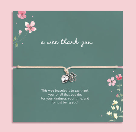 Silver heart and flower charm bracelet on an adjustable cord displayed on a green floral card featuring the Scottish phrase “a wee thank you”. Meaningful thank you gift for friends, teachers, coworkers or loved ones.