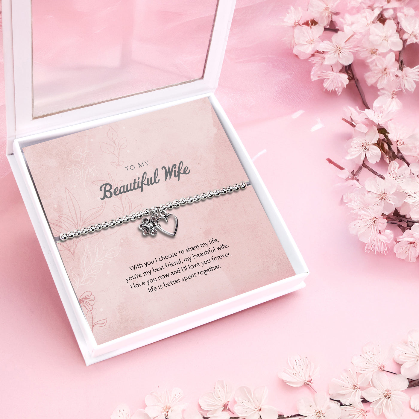 A silver-plated beaded bracelet with a heart and flower charm displayed in a premium keepsake box. The box includes a pink backing card with the message 