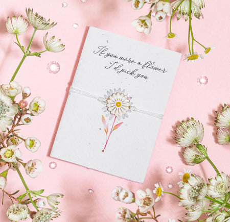A white daisy charm bracelet presented on a seeded greeting card with the message 