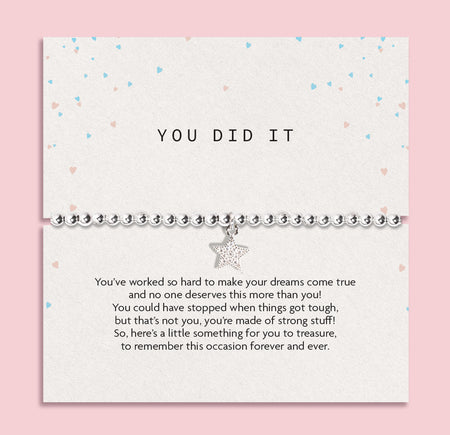 A silver beaded bracelet with a dangling star charm presented on a white 'You Did It' message card, set against a solid pink background.