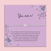 Silver glitter star charm adjustable cord bracelet displayed on a purple "You Did It!" sentiment card with celebration illustrations, including party hats, fireworks and champagne. A thoughtful congratulations gift for graduation, exam success, new job, promotion, achievement or milestone celebration.