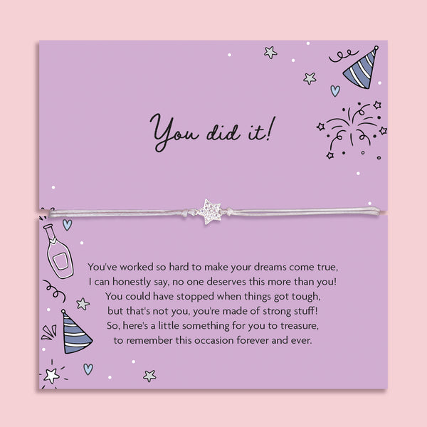 Silver glitter star charm adjustable cord bracelet displayed on a purple "You Did It!" sentiment card with celebration illustrations, including party hats, fireworks and champagne. A thoughtful congratulations gift for graduation, exam success, new job, promotion, achievement or milestone celebration.