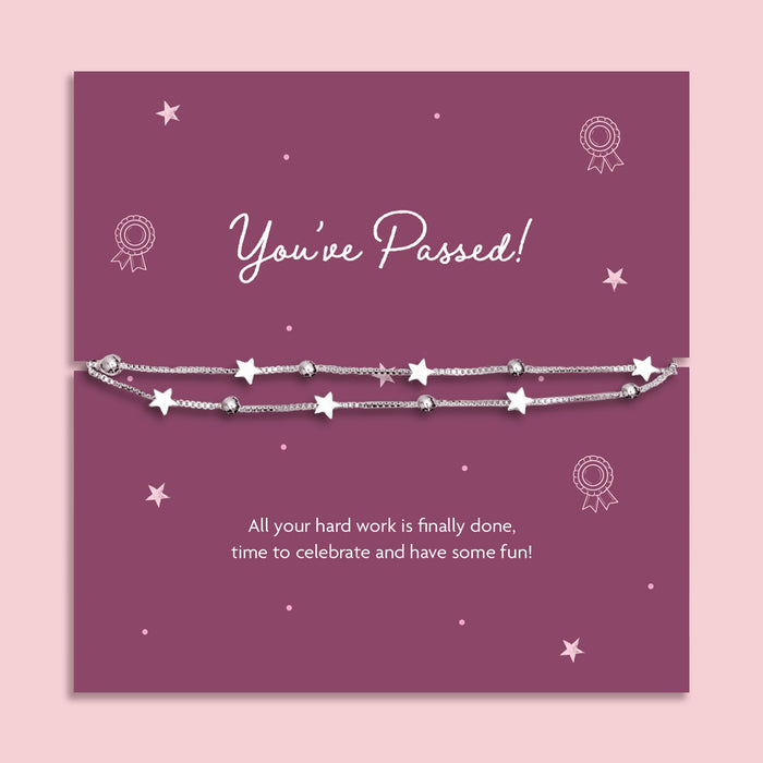 A silver star-themed beaded bracelet displayed on a purple 'You've Passed!' milestone card, set against a light pink background.