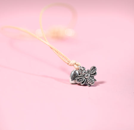 Silver bee-shaped pendant on a pink background