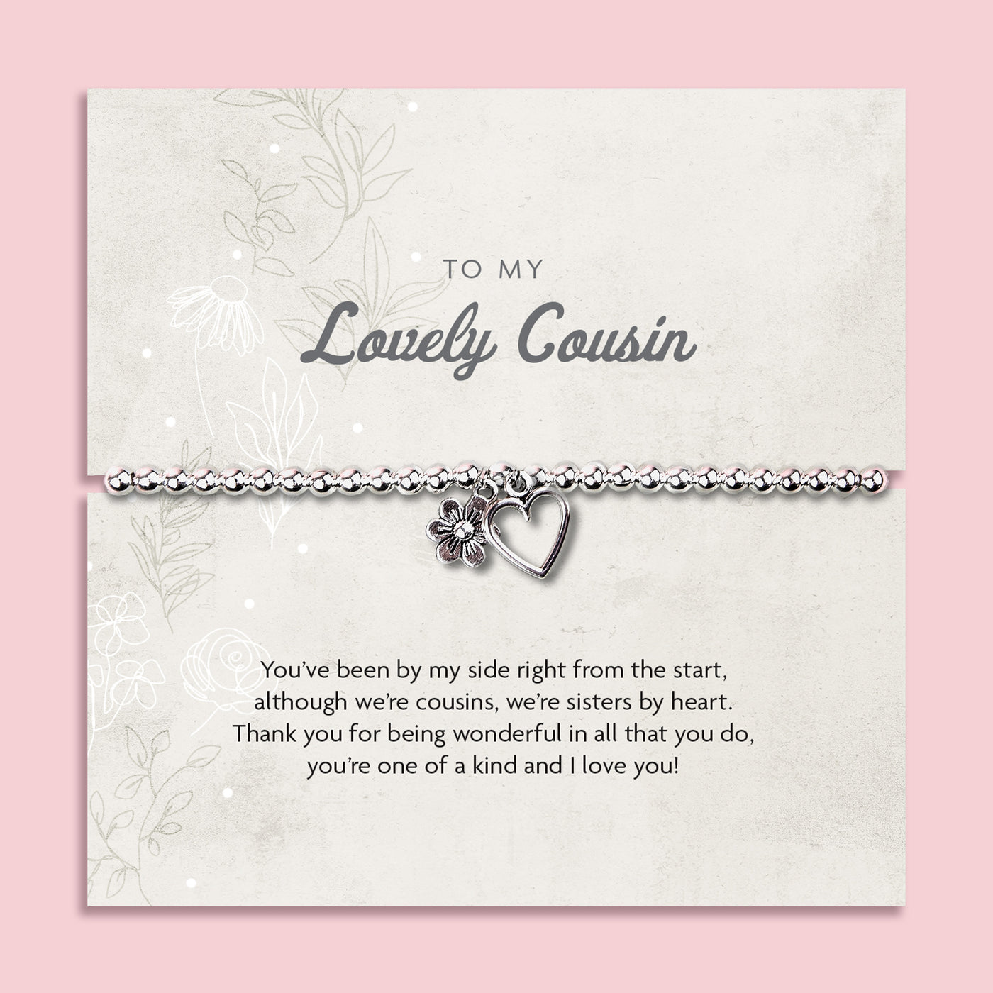 A silver beaded bracelet with a heart and flower charm displayed on a card reading 