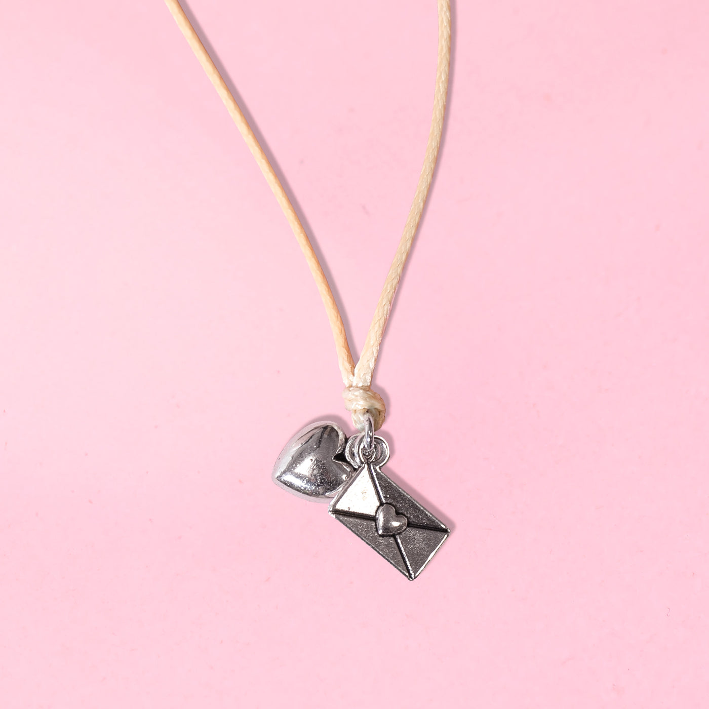 Bracelet with heart and envelope charms on a pink background