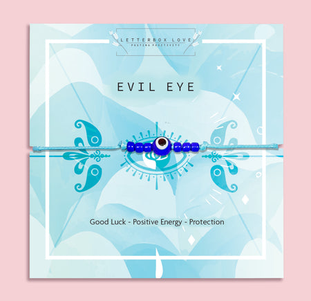 a pink background with a blue 'evil eye' poem card. the bracelet is a blue beaded evil eye charm for good luck and positivity.
