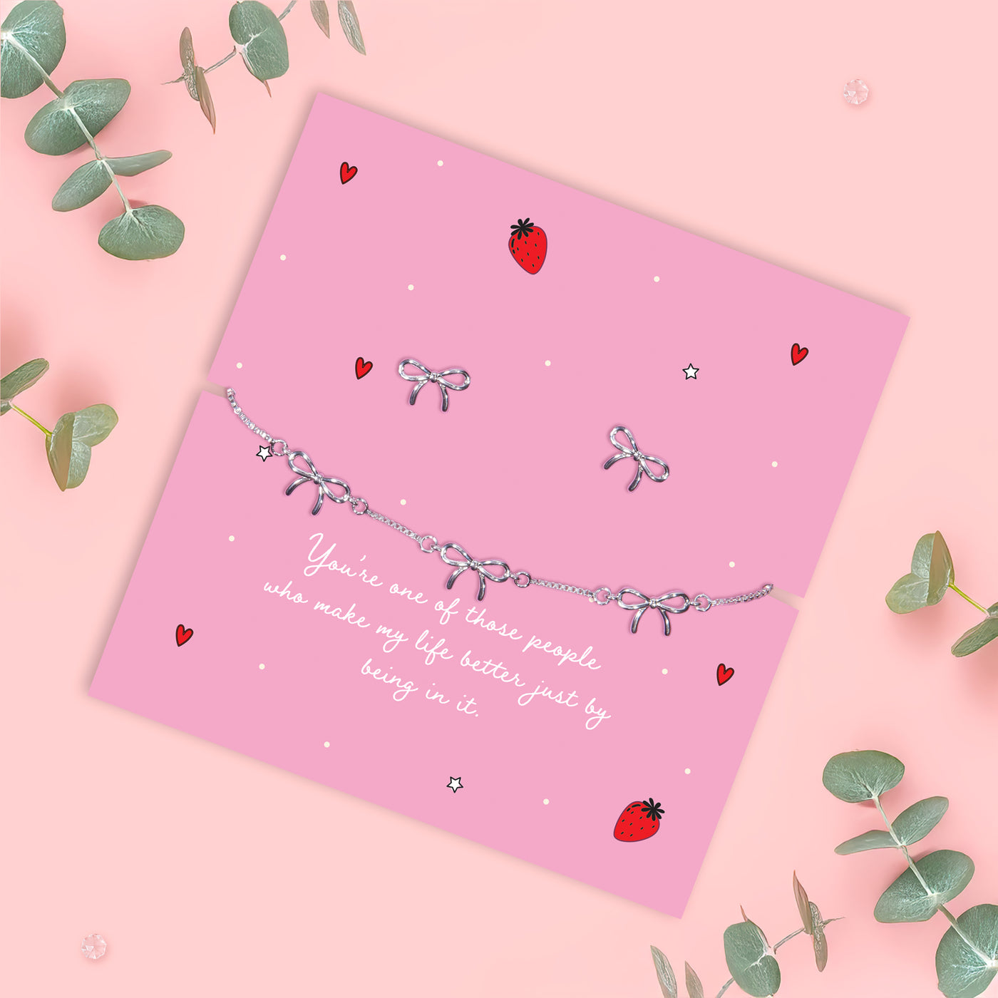 pink background with silver-plated bow bracelets and bow earrings, with eucalyptus decorations