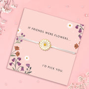 Floral-themed card with a daisy charm bracelet on a pink background. Gypsophila surrounds the card.