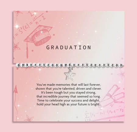 A graduation-themed bracelet displayed on a pink printed card. The bracelet has a silver-toned chain with a dangling silver star charm and small round clear stones.