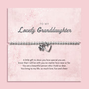 Silver beaded bracelet with heart and flower charms, presented in a white gift box alongside a card titled "Lovely Granddaughter." The card features a heartfelt message celebrating a granddaughter’s special place in your life, filled with love and cheer