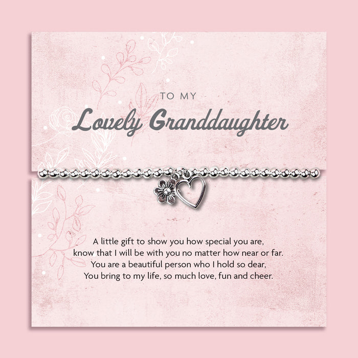 Silver beaded bracelet with heart and flower charms, presented in a white gift box alongside a card titled "Lovely Granddaughter." The card features a heartfelt message celebrating a granddaughter’s special place in your life, filled with love and cheer