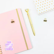 Pink notebook with gold accents and a gold pen on a white background, with a 'you can do hard things' sticker