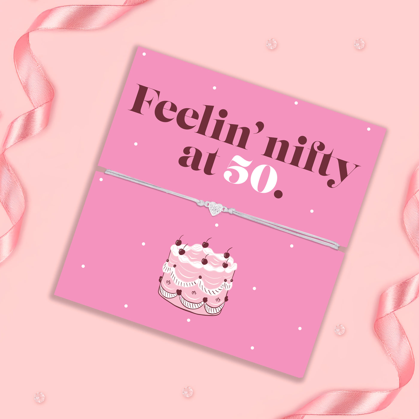 Pink birthday card with cake illustration and text 'Feelin' nifty at 50' on a pink background.