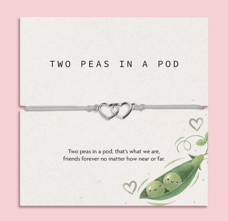 Two Peas in a Pod friendship bracelet with double heart charm on adjustable grey cord, sentimental best friend gift displayed on illustrated keepsake card.
