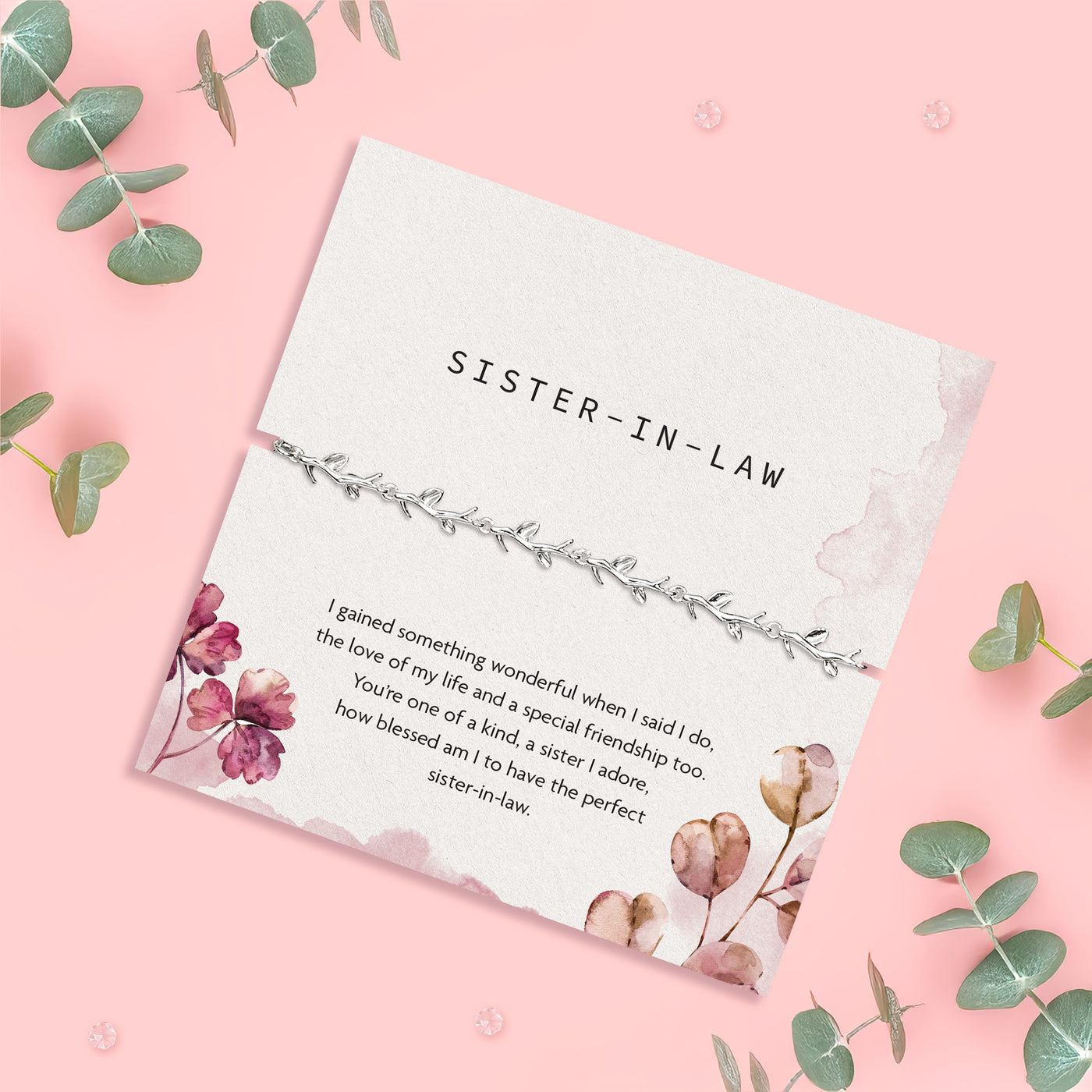 a pink background with sister-in-law poem card can silver-plated vine bracelet surrounded by eucalyptus sprigs