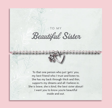 Silver beaded bracelet with heart and flower charms, displayed in a white gift box alongside a card titled 