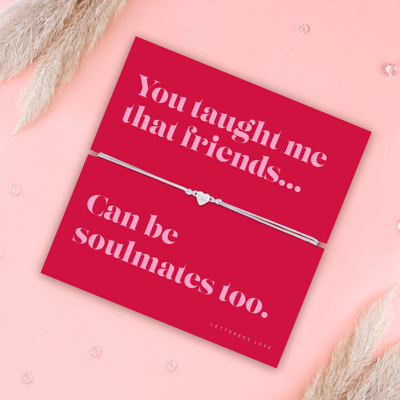 Friendship bracelet with a silver heart charm on an adjustable cord, displayed on a red card reading “You taught me that friends can be soulmates too” — a meaningful bracelet for a friend and thoughtful friendship gift by Letterbox Love. Surrounded by pampus grass