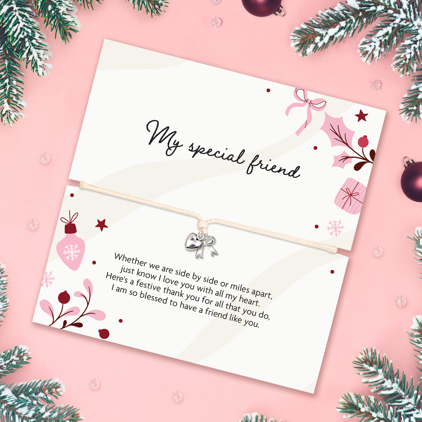 A friendship bracelet gift with a meaningful poem card with festive illustrations. Set on a pink background with Christmas decor scattered around.