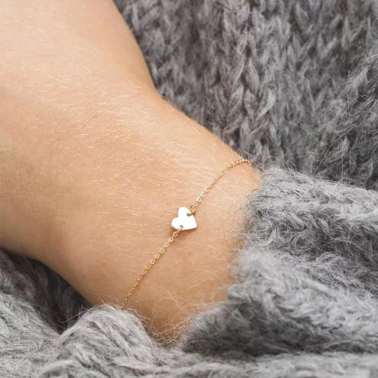 a woman's wrist with an elegant gold heart bracelet. Jewellery to help anxiety and stress