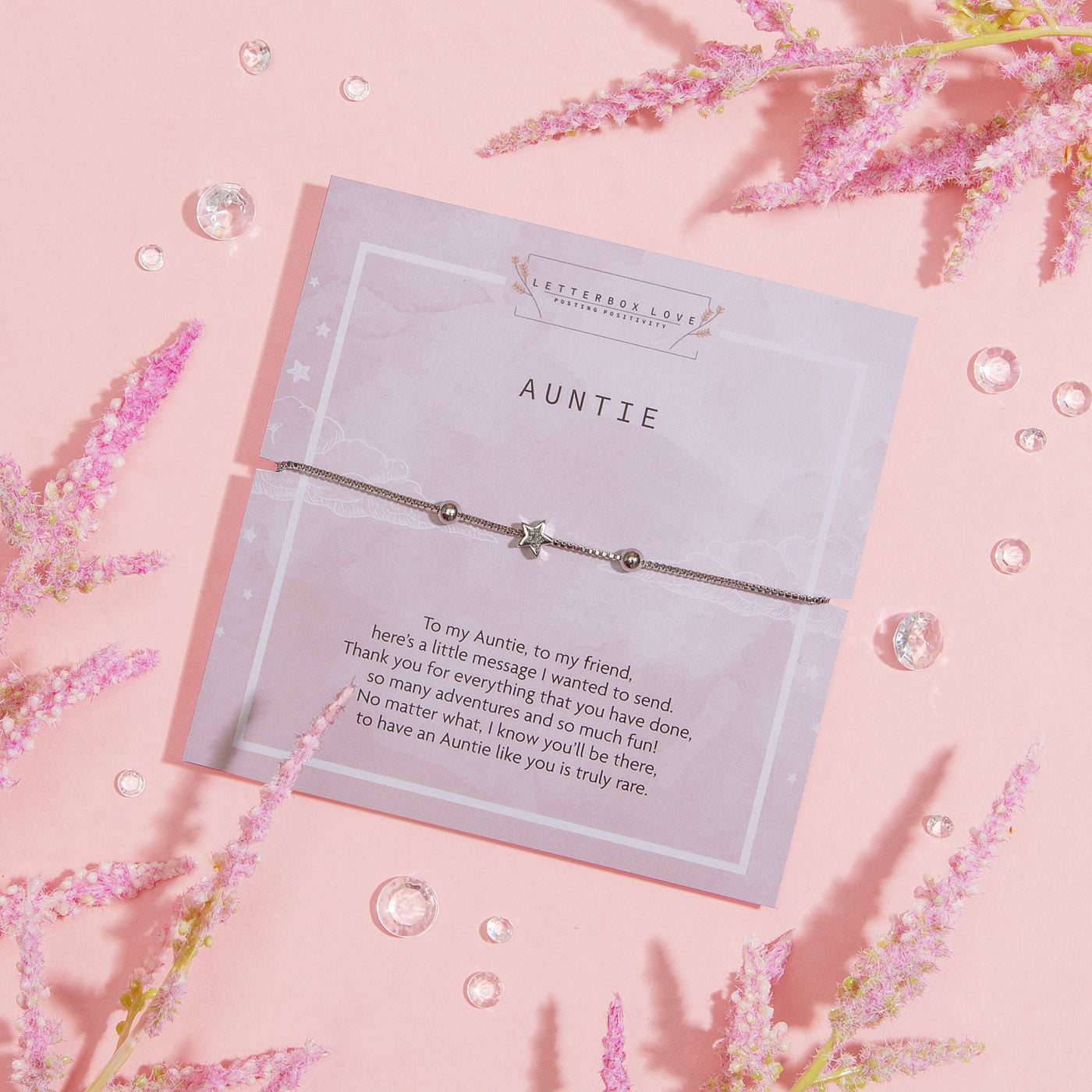 A heartwarming greeting card dedicated to 'Auntie'. The card features a thoughtful message expressing gratitude and admiration. Above the written sentiment is a delicate silver bracelet with a star charm, elegantly placed on the card.