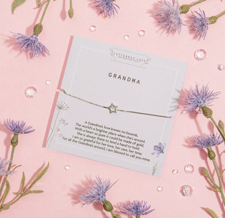 Cherished card titled 'GRANDMA' featuring a touching message about a grandmother's love, adorned by a delicate bracelet with a star charm. Set against a pastel pink backdrop