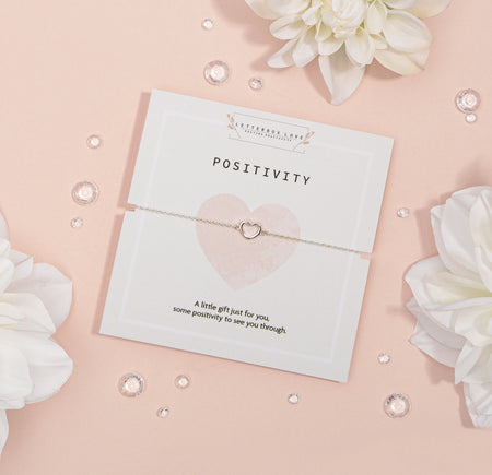 Elegant silver heart-shaped necklace on a 'POSITIVITY' card with the message 'A little gift just for you, some positivity to see you through.