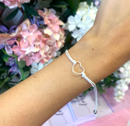 a woman's wrist with a white string bracelet and a floral background